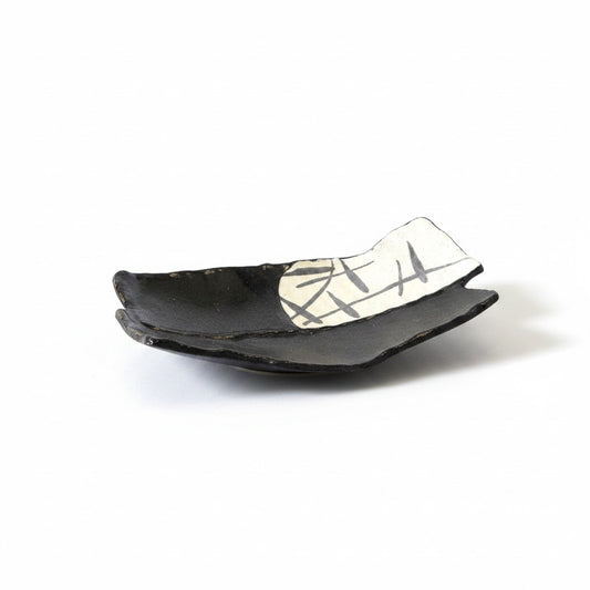 Plat rectangulaire Yugen lab en céramique noire et blanche avec motifs graphiques et pieds sur fond blanc