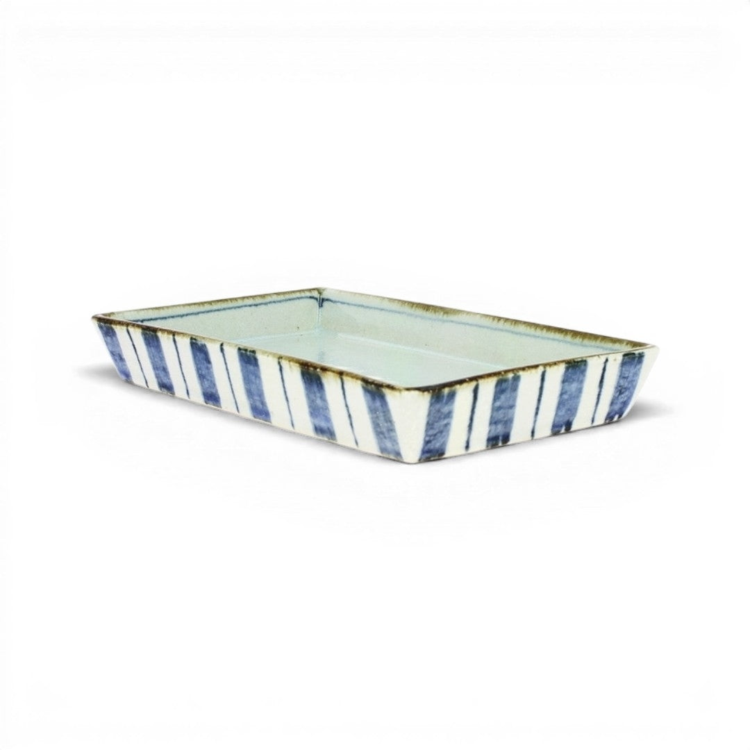 White ceramic Japanese rectangular dish with high edges striped in indigo blue tokusa, on a white background