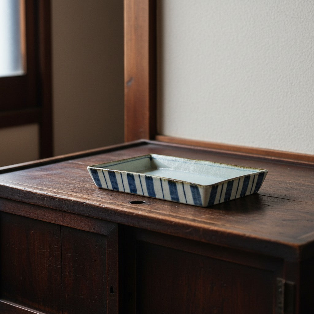 Plat rectangulaire Yugen lab en porcelaine japonaise avec motif à rayures bleues et blanches sur une table en bois