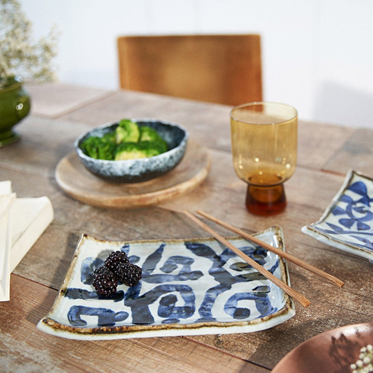 Plat à sushi Yugen lab en céramique blanche avec motifs bleus traditionnels et bords incurvés sur une table en bois