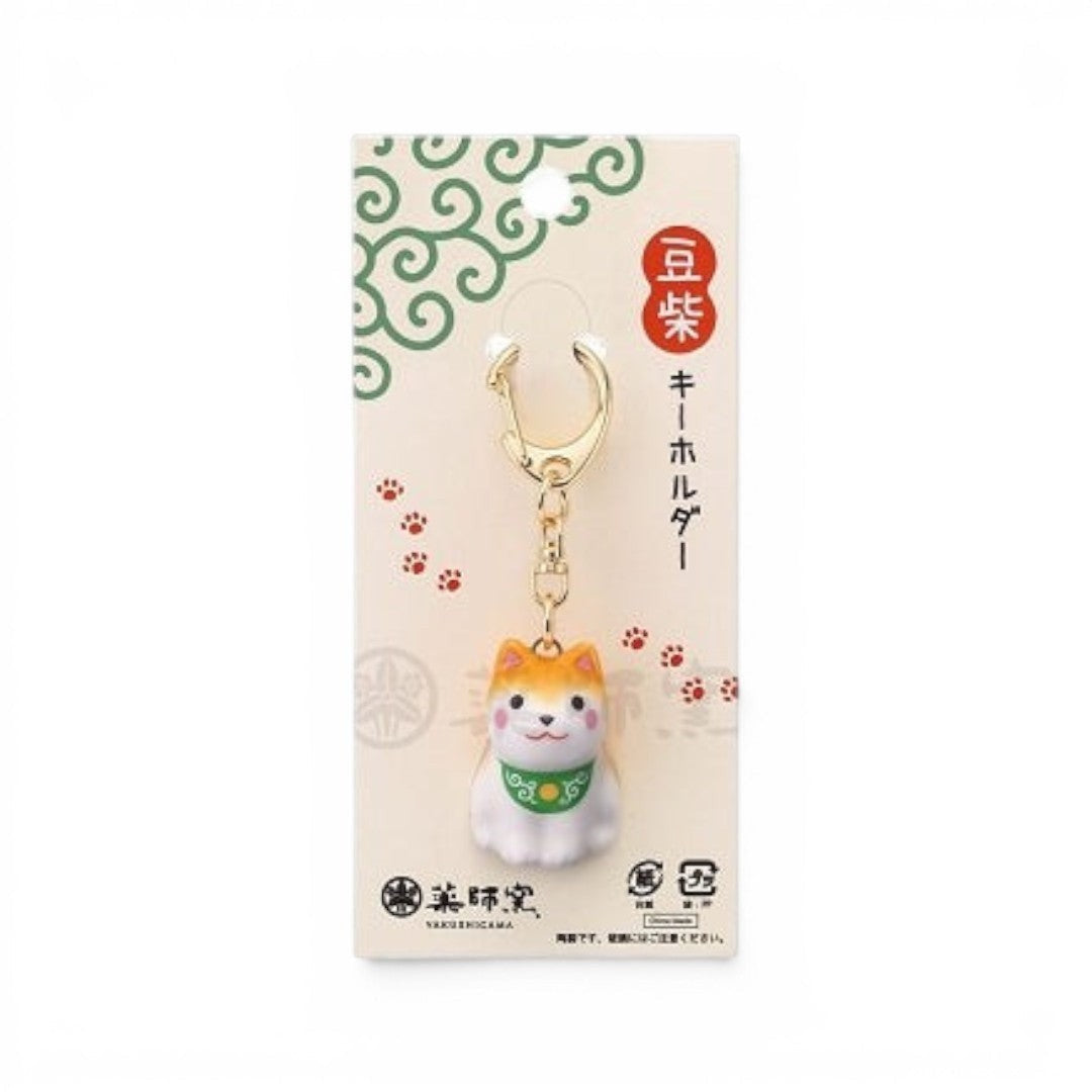 Porte-clés Yugen lab en porcelaine représentant un chien Mameshiba avec un collier vert sur support cartonné décoré
