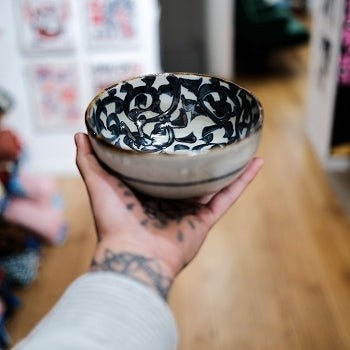Saladier en céramique Yugen lab avec motif pieuvre noir et blanc tenu à la main dans une boutique artisanale