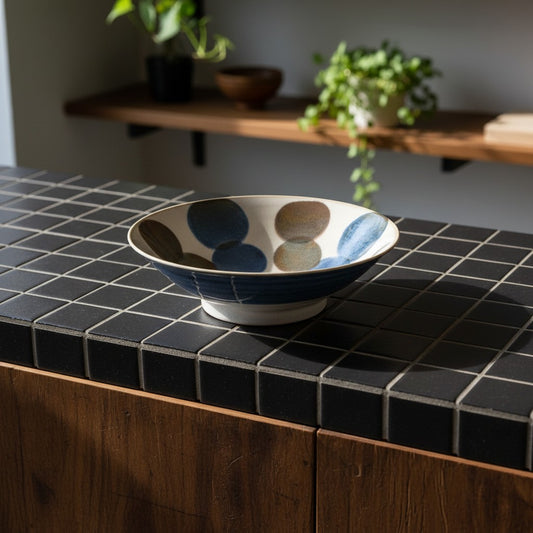 Saladier en porcelaine japonaise Yugen lab avec motifs peints bleus et marron sur comptoir en carrelage noir