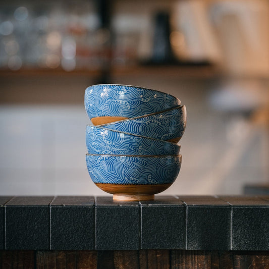 Set de quatre bols japonais Yugen lab en céramique bleue et blanche avec motif de vagues Nami empilés sur un comptoir