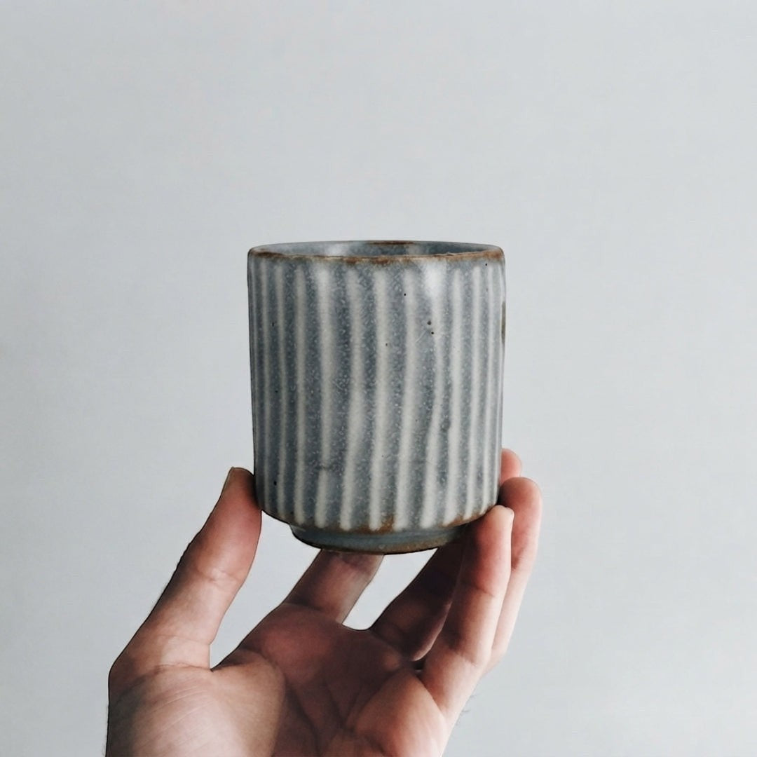 Tasse Yugen lab en céramique grise avec relief blanc, style wabi-sabi minimaliste tenue en main