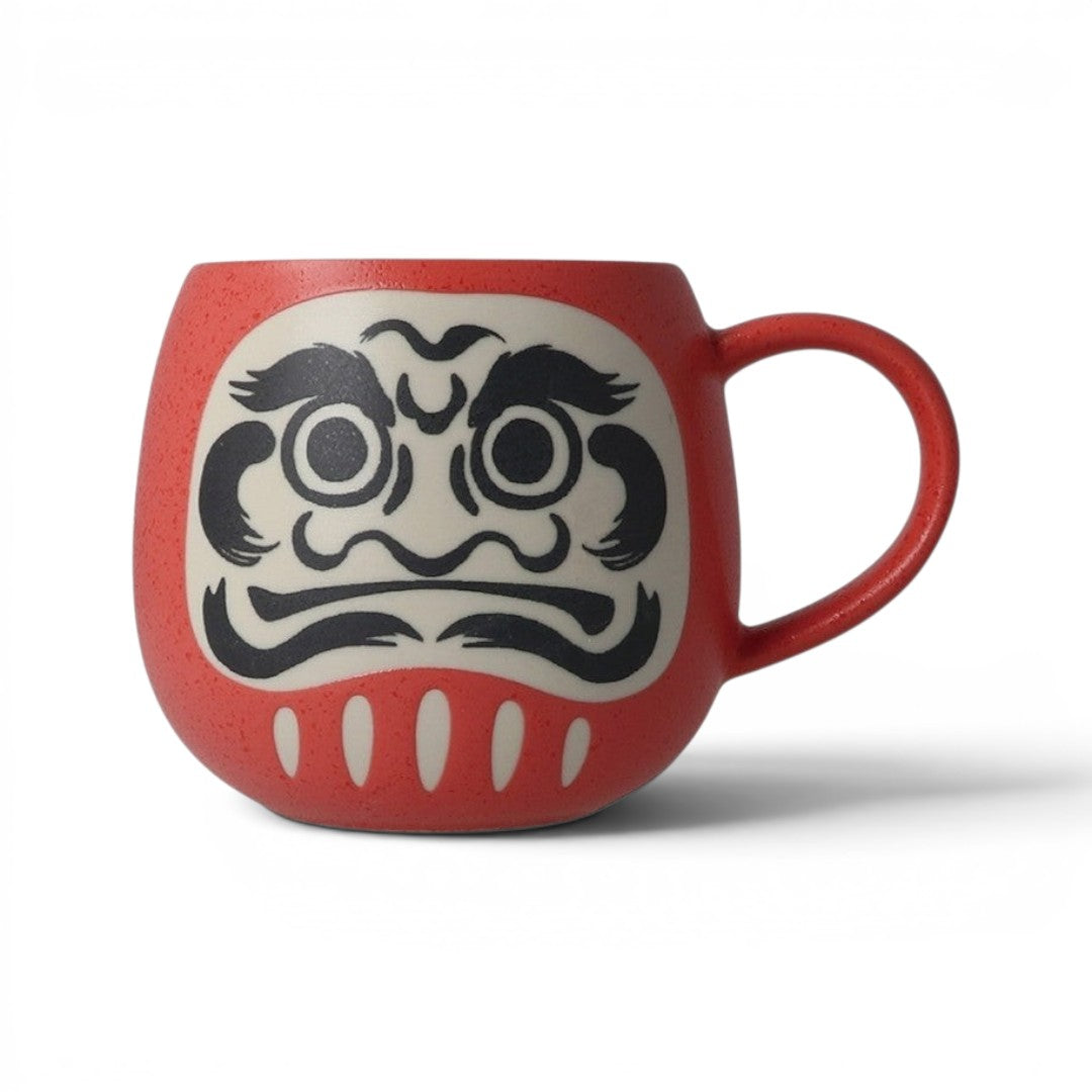Tasse Yugen lab en porcelaine rouge avec motif Daruma traditionnel noir, forme arrondie et texturée.