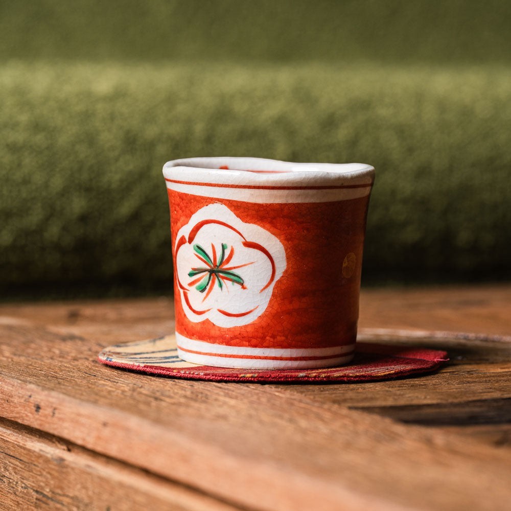 Tasse japonaise Yugen lab en porcelaine rouge avec motif floral traditionnel posée sur une table en bois