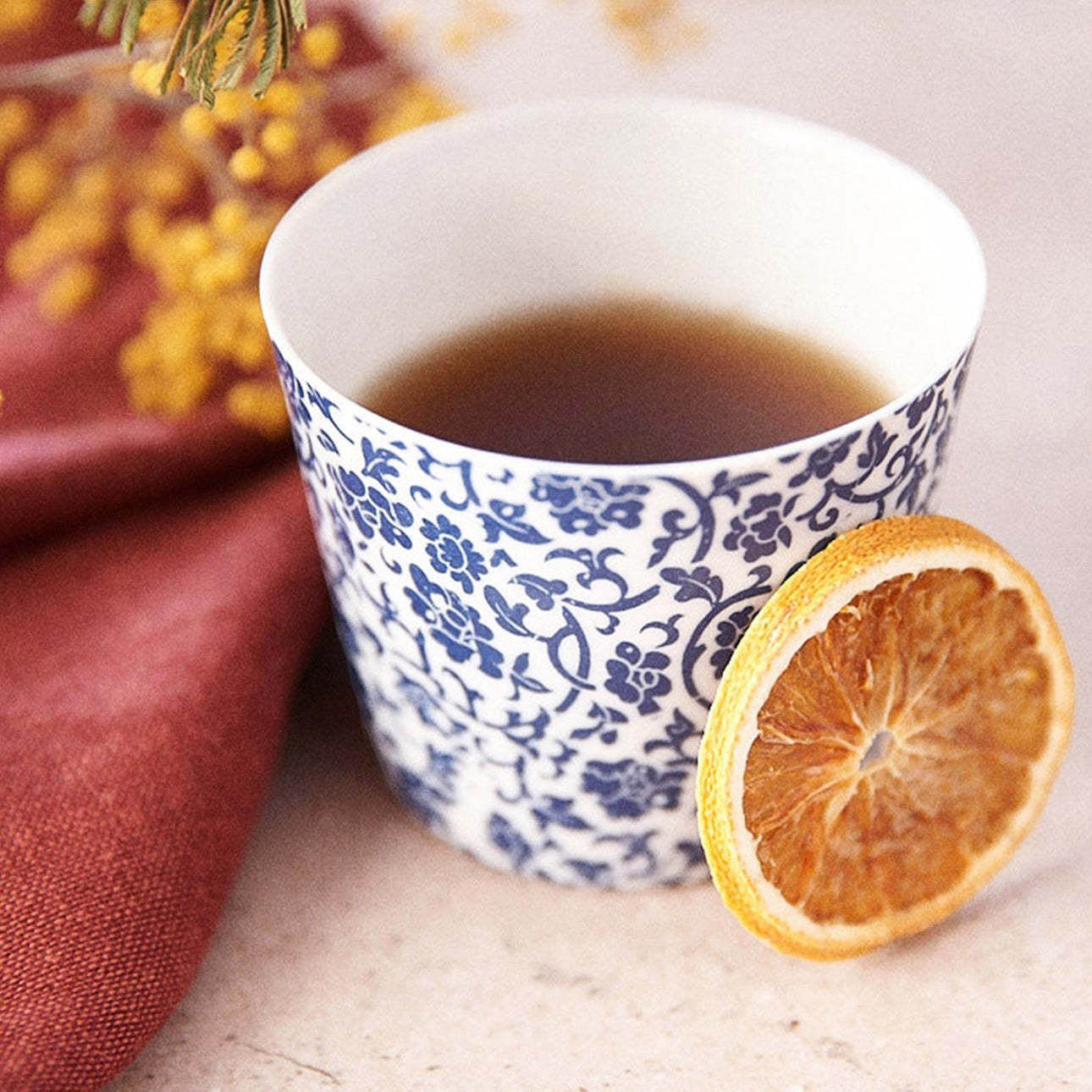 Tasse à thé Yugen lab en porcelaine fine bleue à motifs floraux traditionnels japonais avec une tranche d'orange séchée