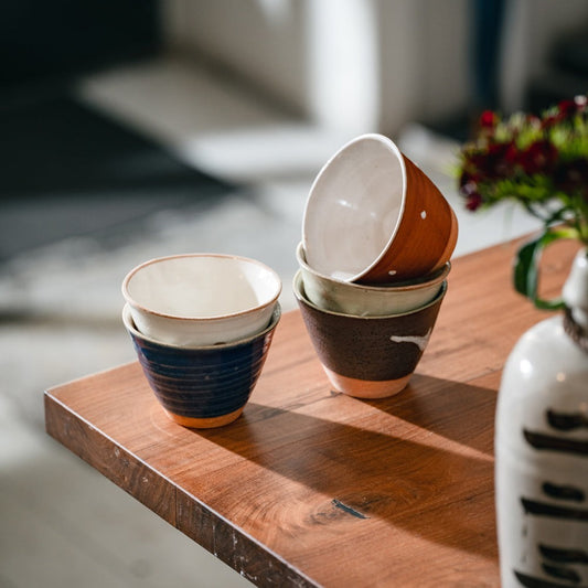Lot de 5 tasses Yugen lab en céramique artisanale japonaise aux tons terreux et bleus sur une table en bois