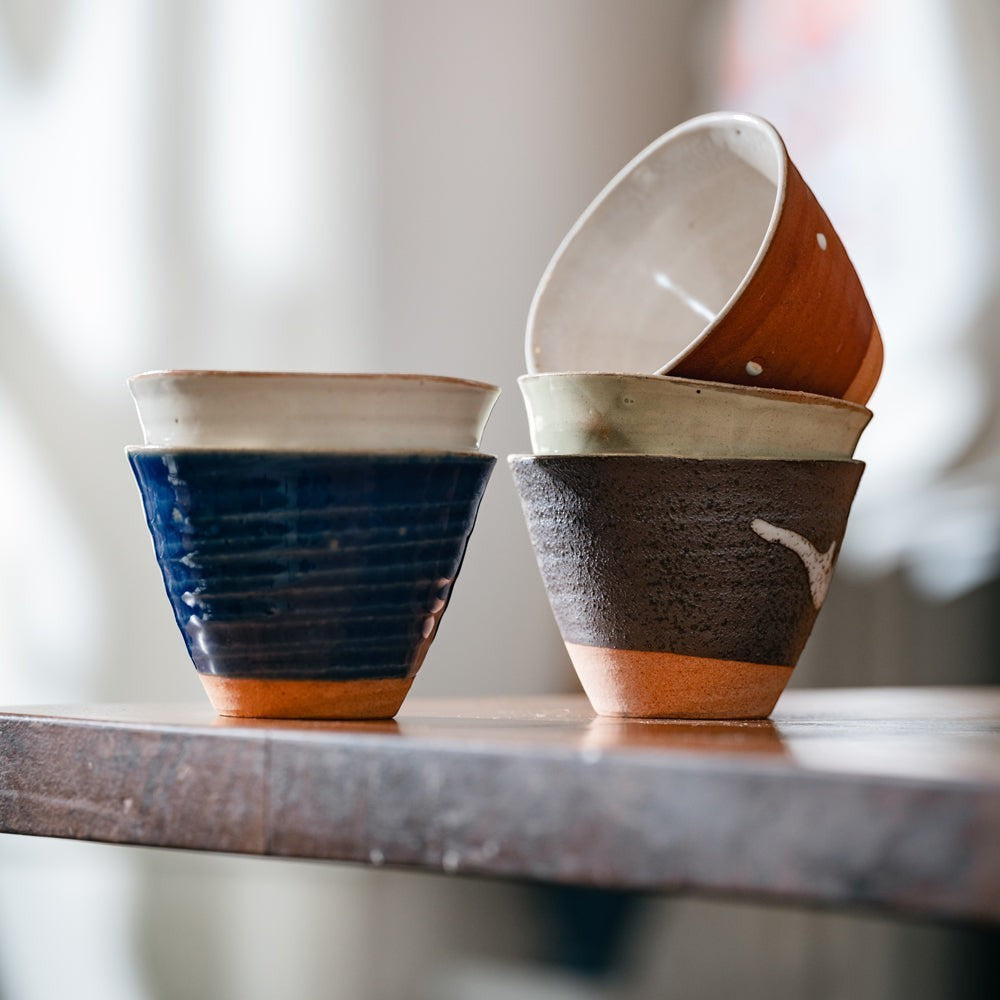 Lot de 5 tasses Yugen lab en céramique artisanale japonaise aux textures et couleurs variées sur une table en bois