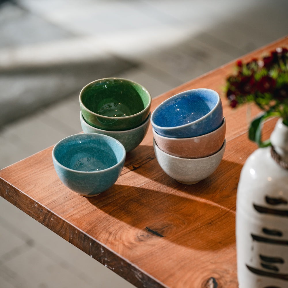 Tasses japonaises en céramique Yugen lab aux couleurs variées empilées sur une table en bois
